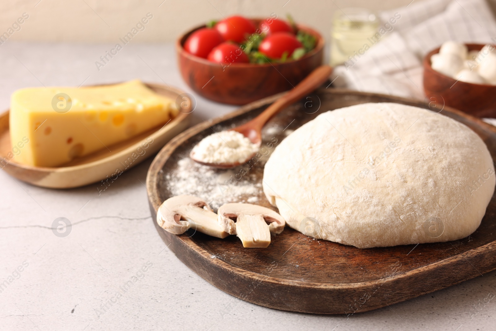 Photo of Pizza dough and products on gray textured table, closeup