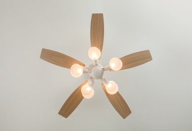 Photo of Modern ceiling fan with lamps indoors, bottom view. Interior element