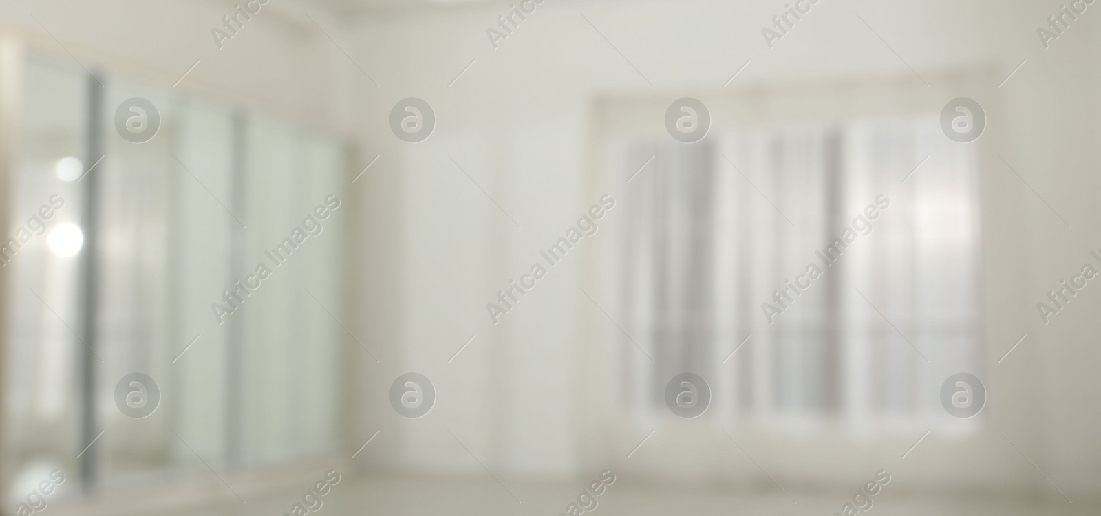 Photo of Empty room with white walls and large window, blurred view