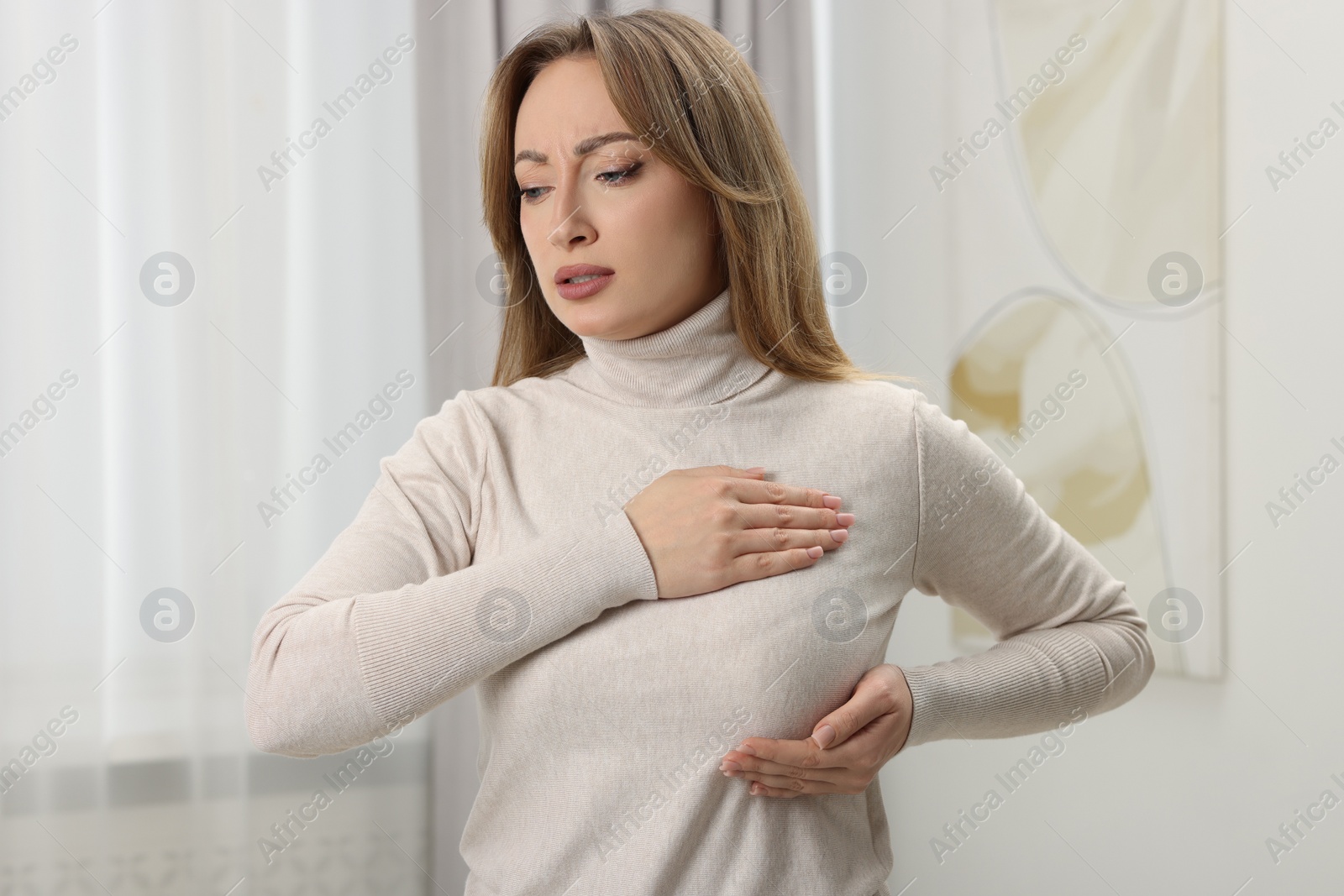 Photo of Mammology. Young woman doing breast self-examination at home