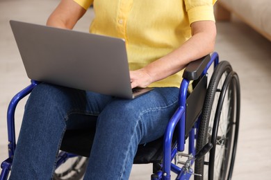 Photo of Woman in wheelchair using laptop indoors, closeup