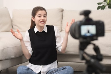 Photo of Smiling teenage blogger explaining something while streaming at home