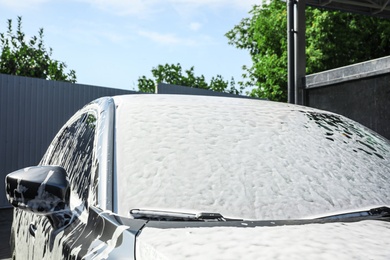 Automobile covered with foam at car wash, closeup of windshield