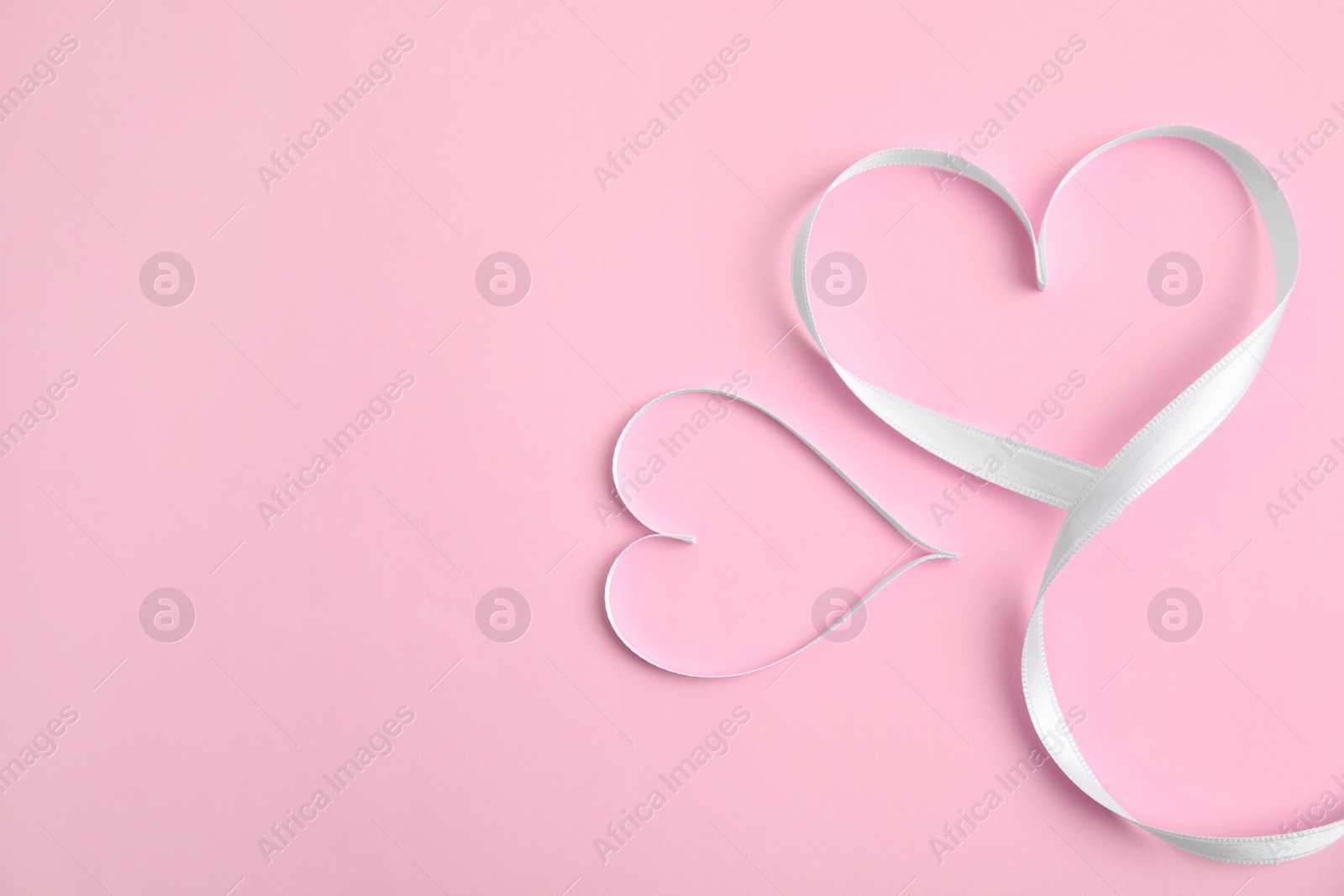 Photo of Hearts made of white ribbon on pink background, flat lay with space for text. Valentine's day celebration