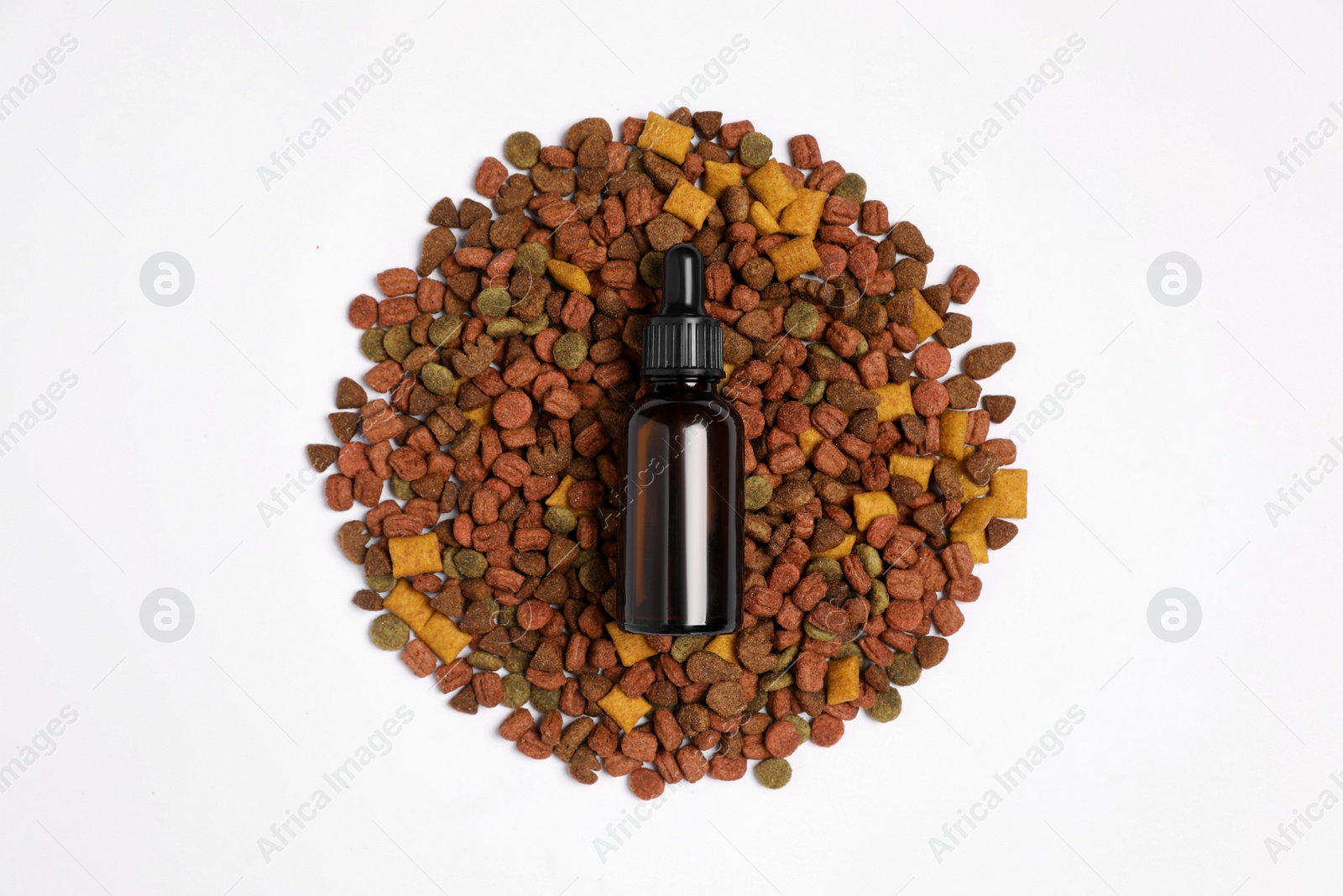 Photo of Glass bottle of tincture and dry pet food on white background, top view