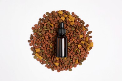Photo of Glass bottle of tincture and dry pet food on white background, top view