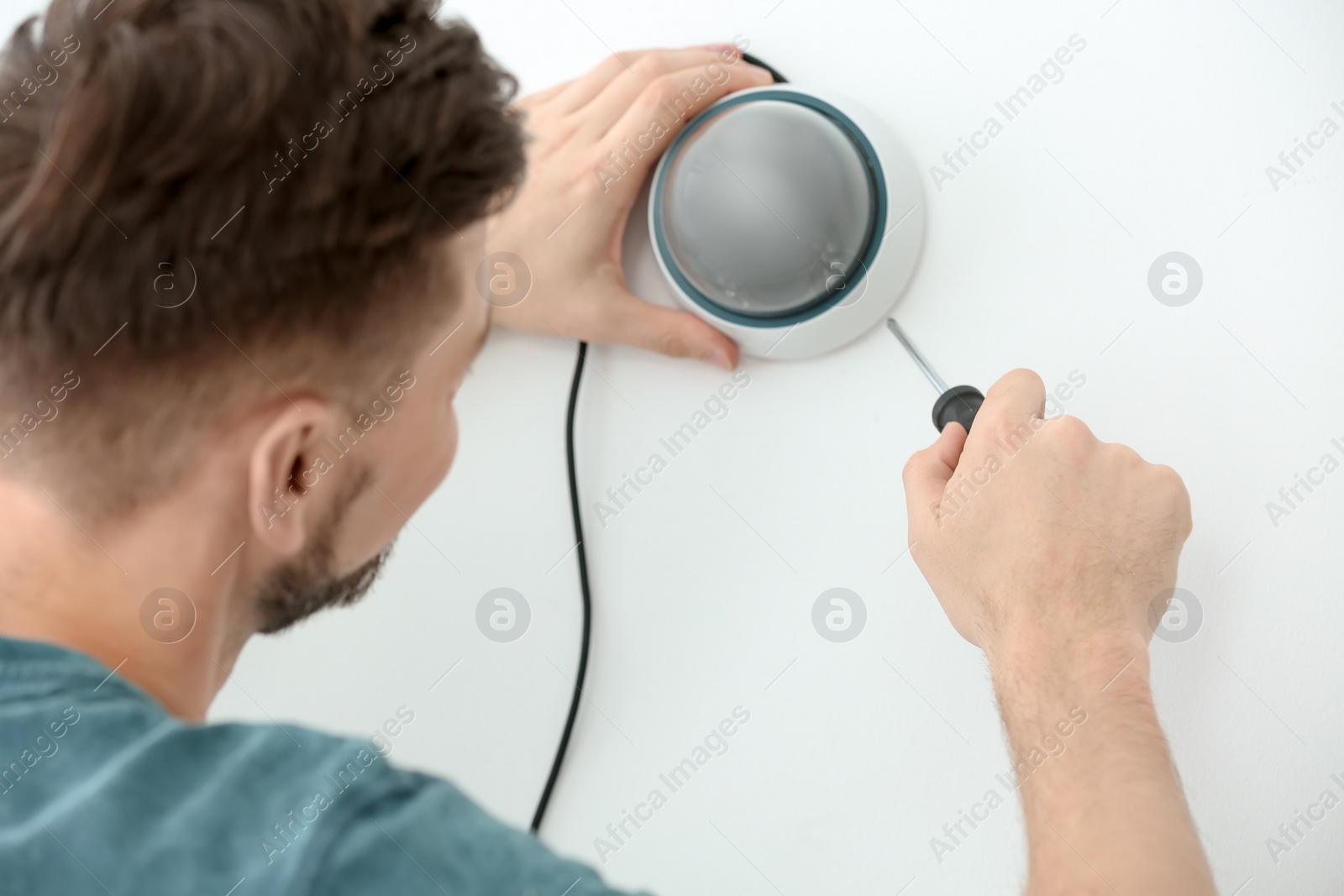 Photo of Technician installing CCTV camera on wall indoors