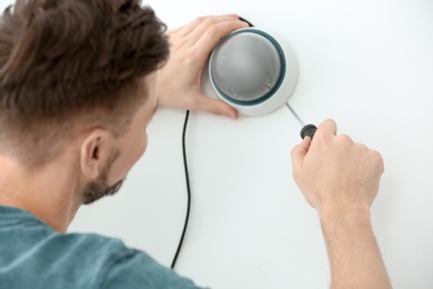 Photo of Technician installing CCTV camera on wall indoors