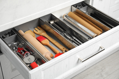 Photo of Different utensils in open desk drawer indoors