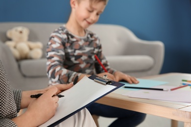 Female psychologist working with cute little boy in office