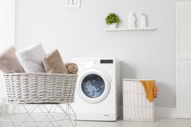 Photo of Basket with laundry and washing machine on background. Space for text
