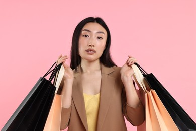 Photo of Beautiful woman with shopping bags on pink background