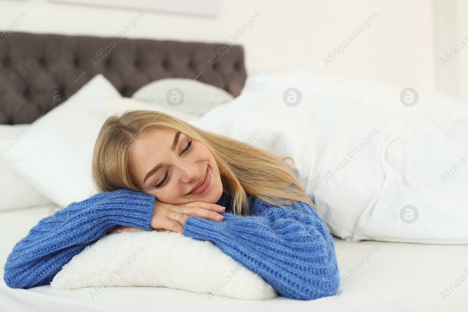 Photo of Beautiful young woman lying on pillow in bed at home. Winter atmosphere