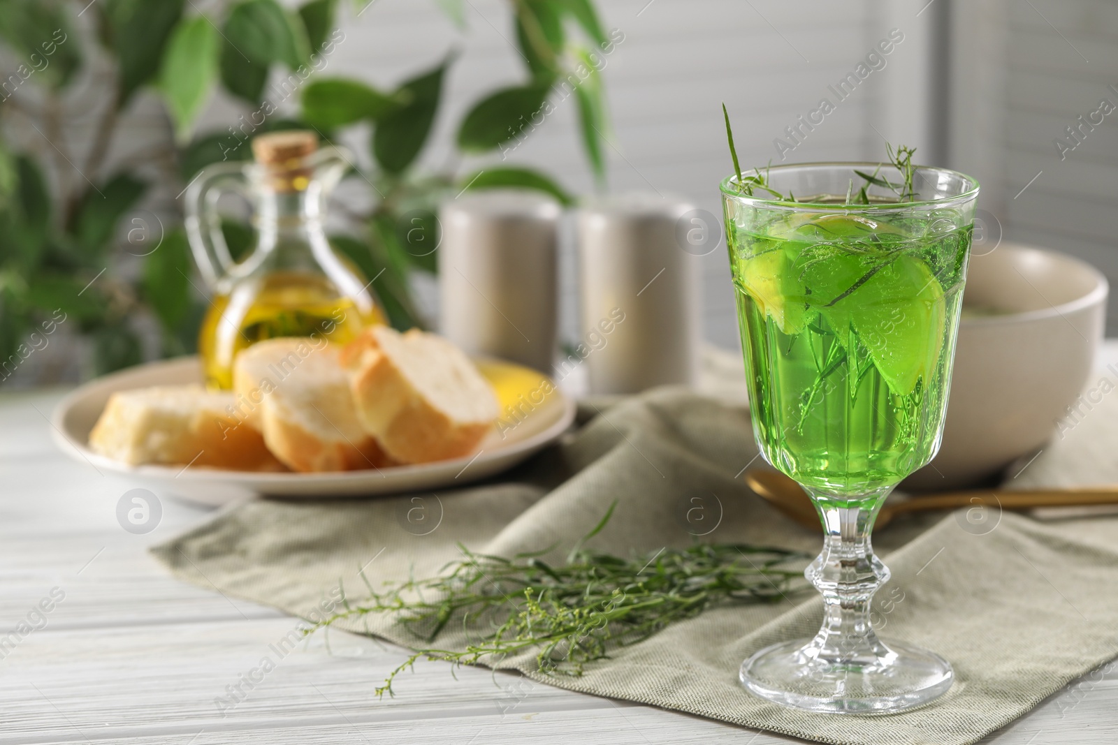 Photo of Delicious drink with tarragon in glass on white wooden table. Space for text