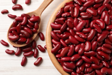 Photo of Raw red kidney beans with bowl and spoon on white wooden table, top view