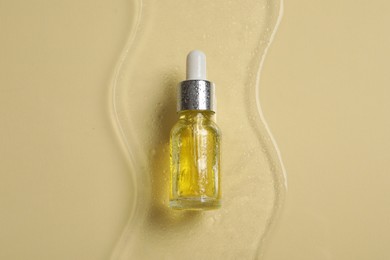 Bottle of cosmetic serum on beige background, top view