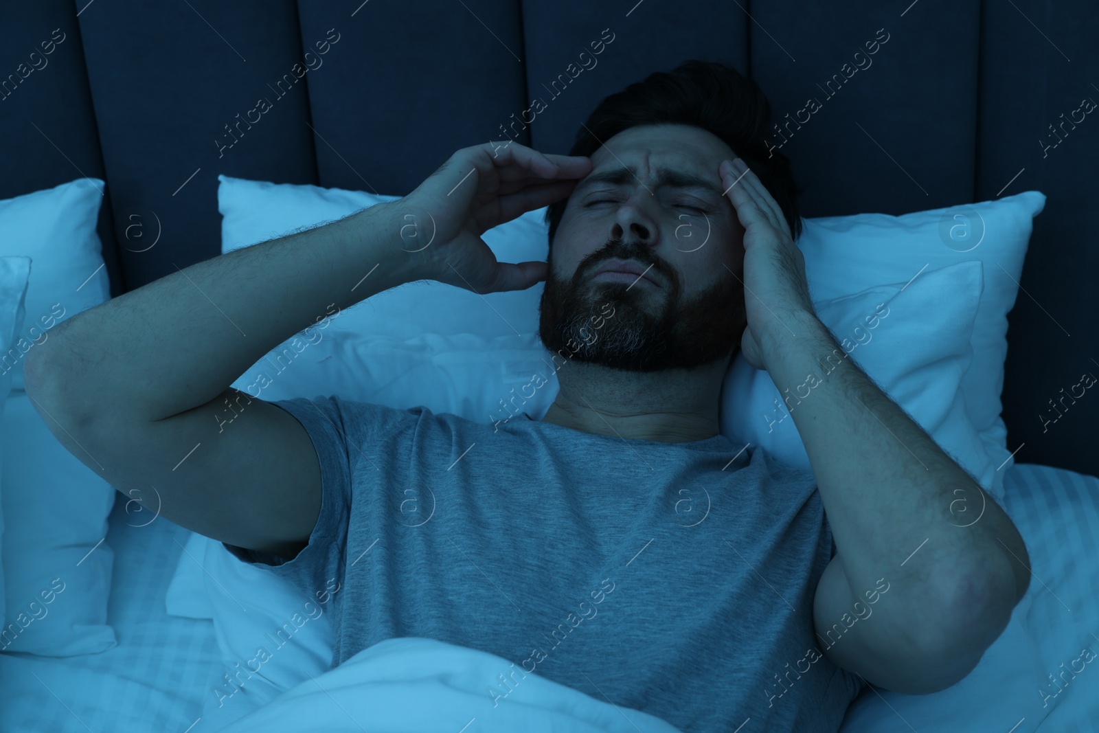 Photo of Man suffering from headache in bed at night