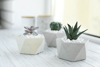 Photo of Beautiful succulent plants in stylish flowerpots on windowsill. Home decor