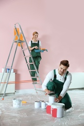 Photo of Professional decorators painting wall indoors. Home repair service