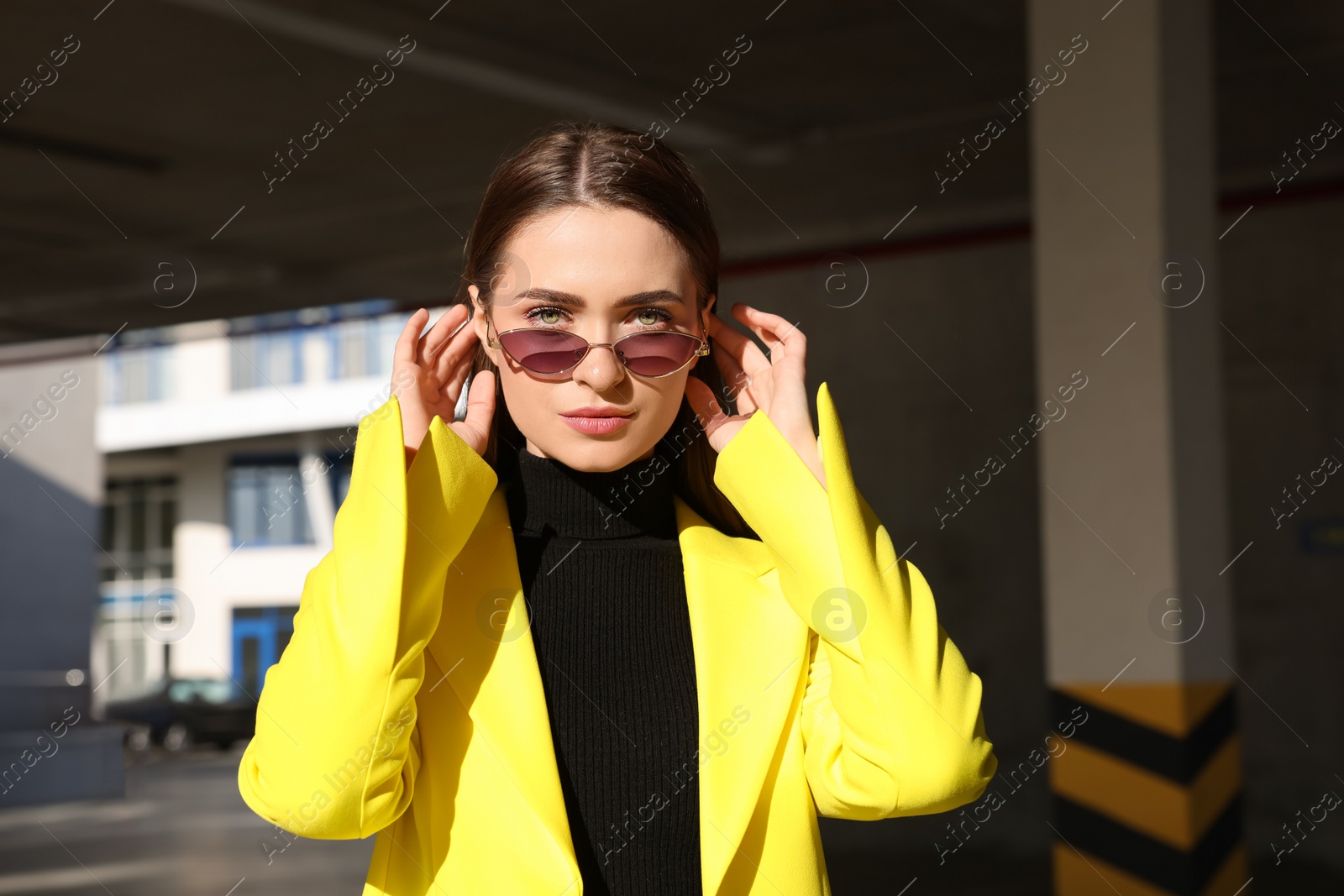 Photo of Fashionable young woman wearing stylish outfit with yellow jacket in open parking garage