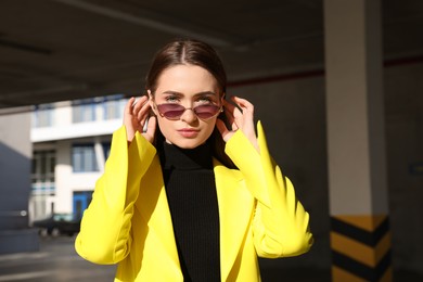 Photo of Fashionable young woman wearing stylish outfit with yellow jacket in open parking garage