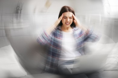 Image of Young woman with laptop suffering from migraine at home