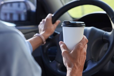 Photo of Coffee to go. Woman with paper cup of drink driving her car, closeup