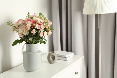 Photo of Beautiful bouquet of fresh flowers in vase on chest of drawers indoors