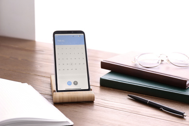 Photo of Smartphone with calendar app on wooden table