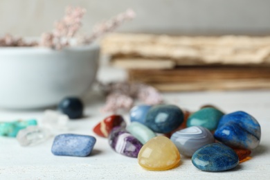 Pile of different gemstones on white wooden table. Space for text