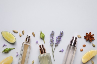 Photo of Flat lay composition with bottles of perfume, citrus fruits and flowers on light grey background. Space for text