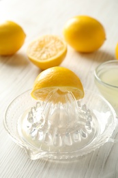 Photo of Plastic juicer with half of lemon on white wooden table