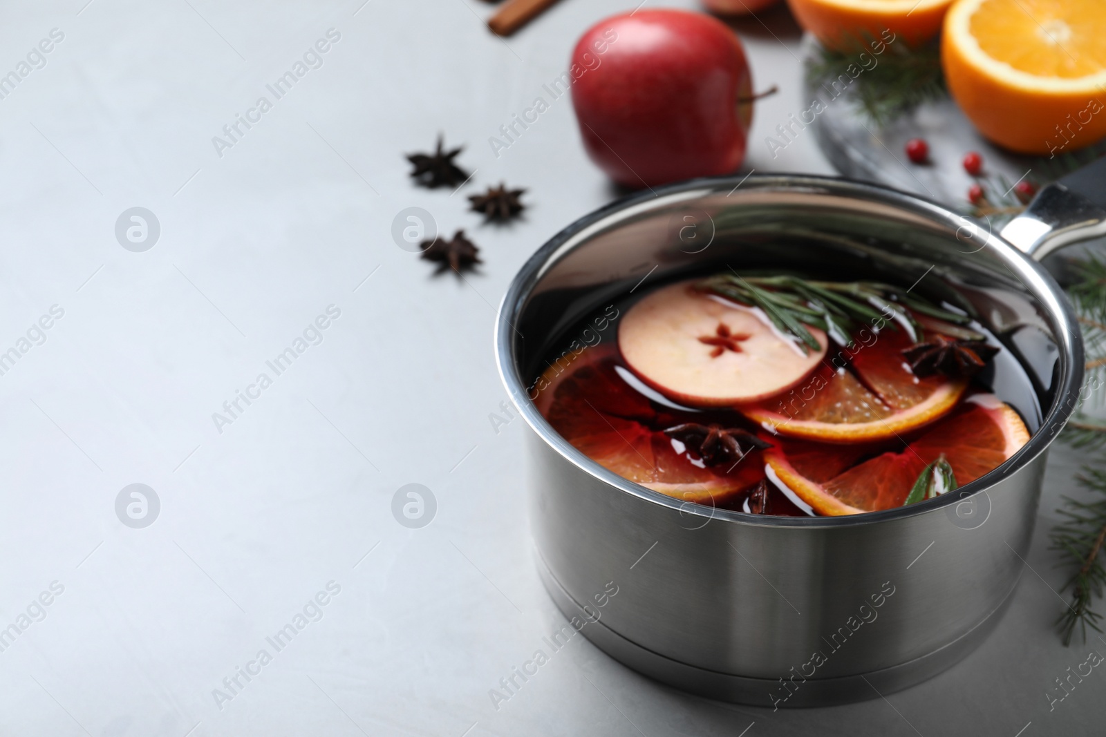 Photo of Saucepan with tasty mulled wine on grey table. Space for text