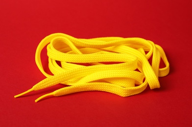 Photo of Yellow shoe lace on red background. Stylish accessory