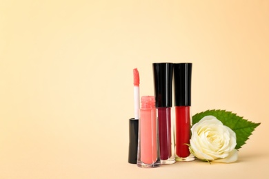 Photo of Lip glosses and flower on color background