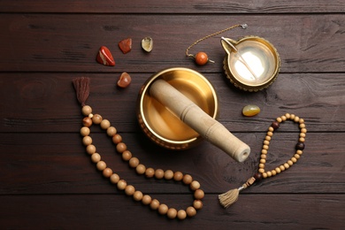 Flat lay composition with golden singing bowl on wooden table. Sound healing
