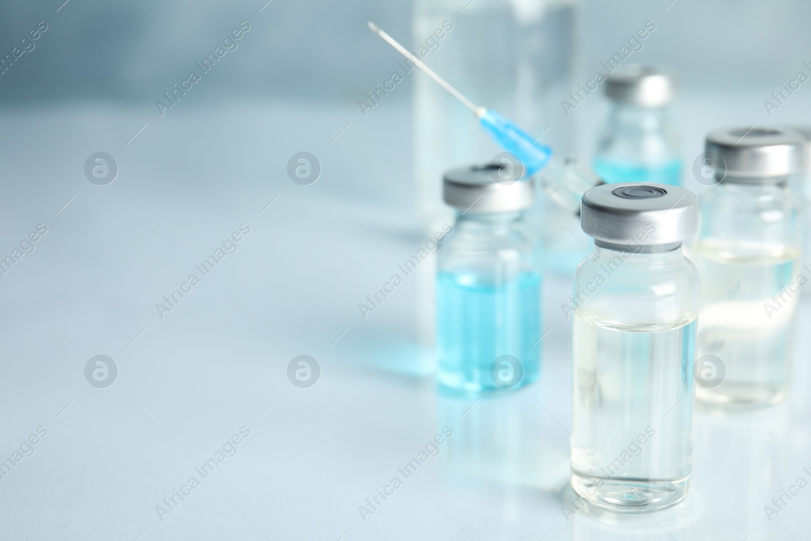 Photo of Vials and syringe on light table, space for text. Vaccination and immunization