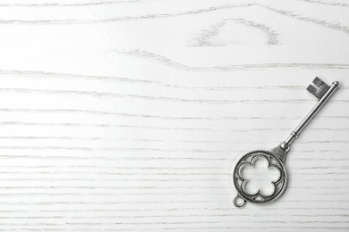 Photo of Old vintage key on wooden background, top view with space for text