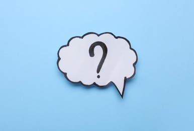 Paper speech bubble with question mark on light blue background, top view