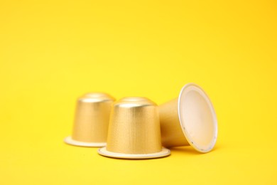 Photo of Three coffee capsules on yellow background, closeup