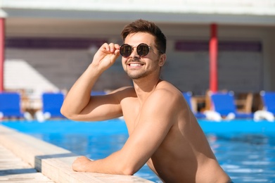 Photo of Handsome young man at swimming pool edge on sunny day