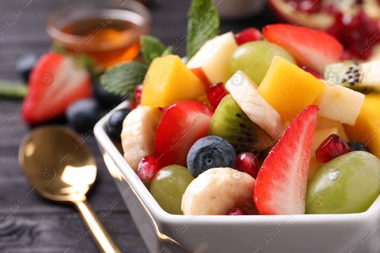 Photo of Delicious fresh fruit salad in bowl on table, closeup view
