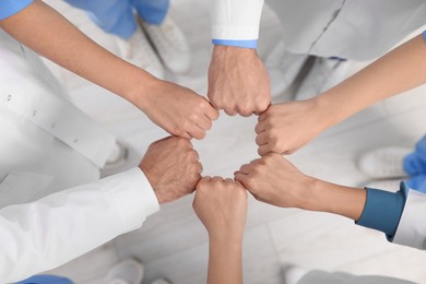 Photo of Team of medical doctors putting hands together indoors, above view