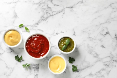 Set of different delicious sauces on white marble table, top view. Space for text