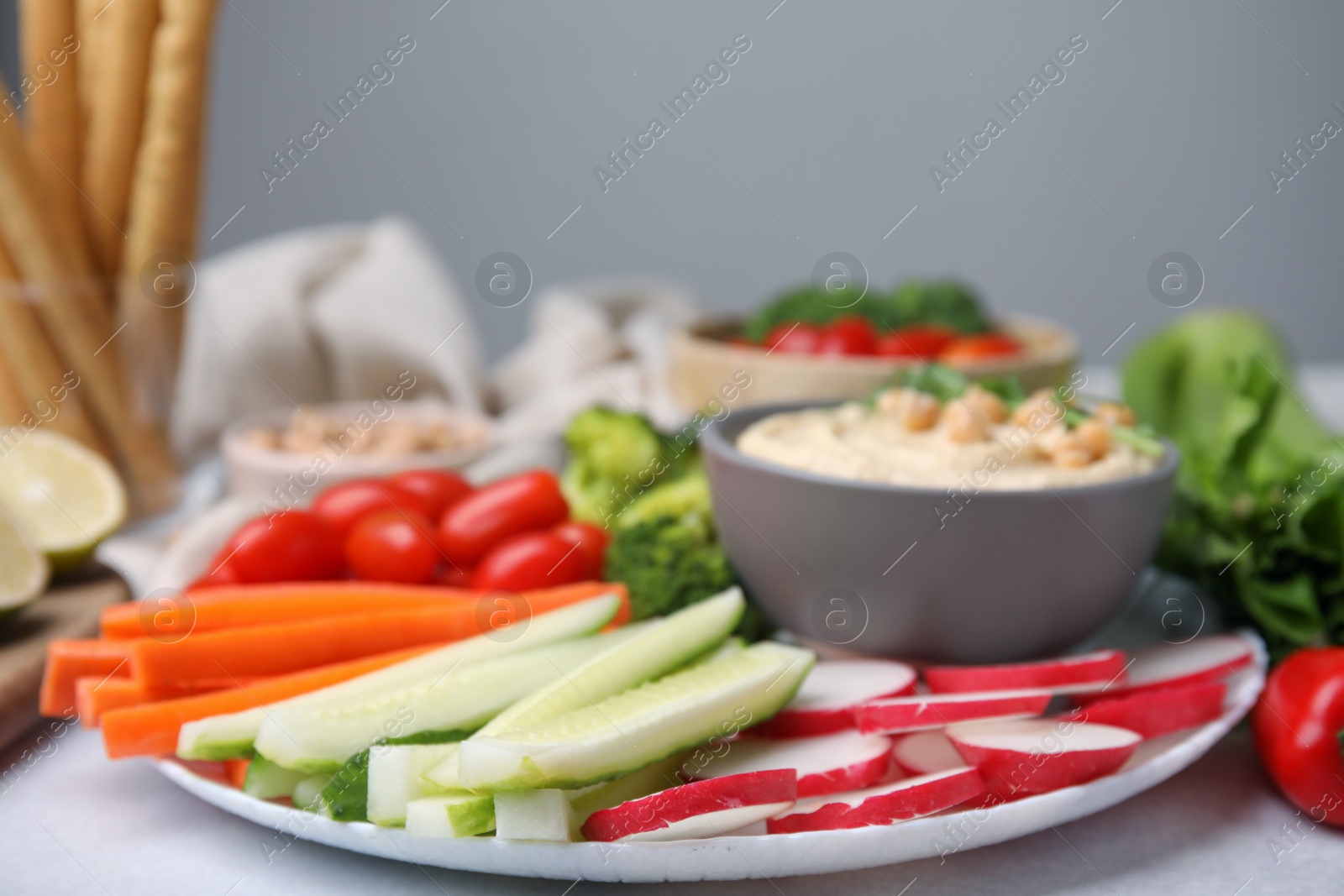 Photo of Plate with delicious hummus and fresh vegetables on table