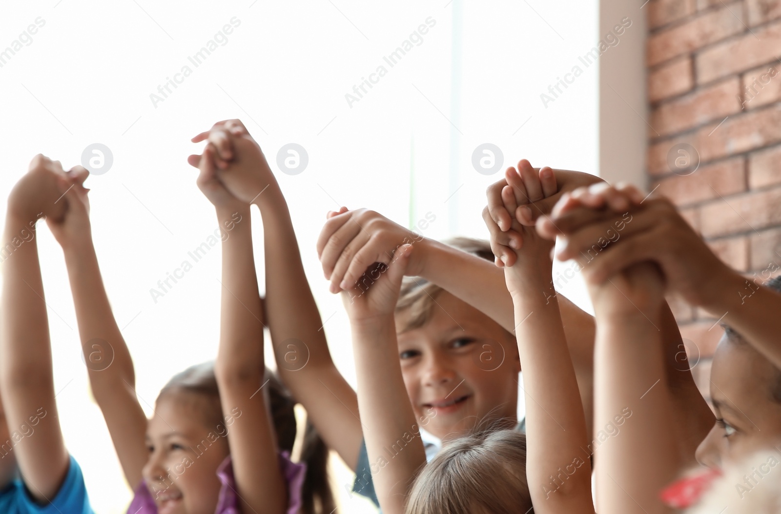 Photo of Little children holding hands together indoors. Unity concept