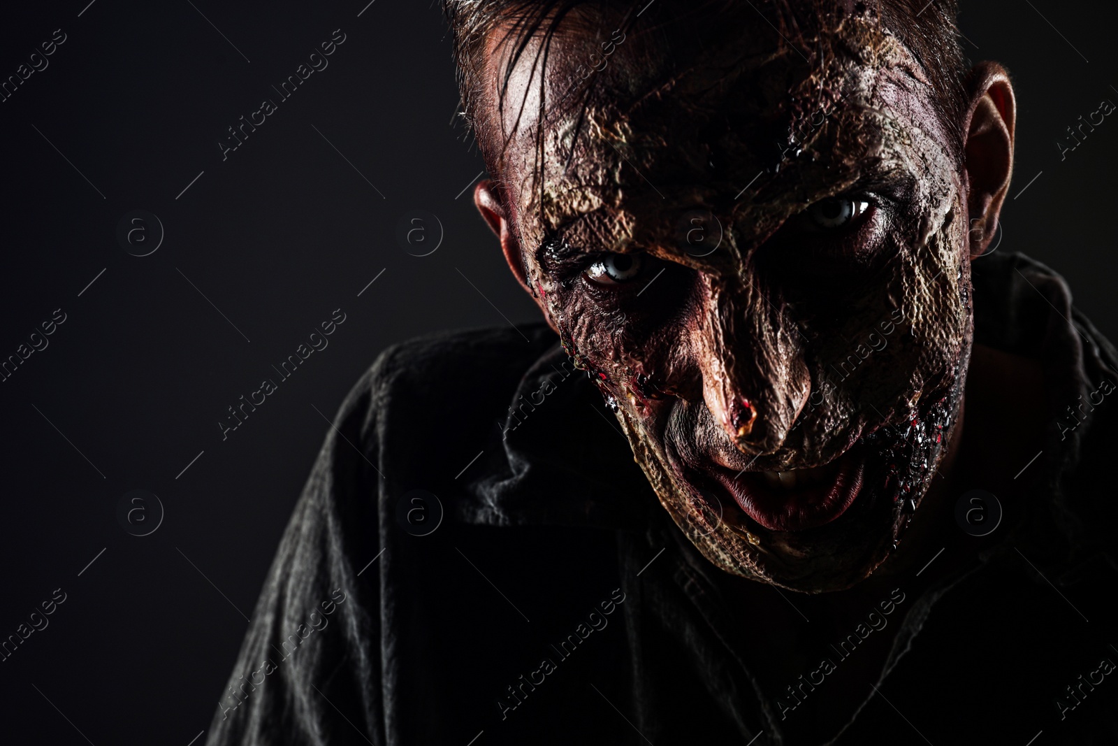 Photo of Scary zombie on dark background, closeup. Halloween monster