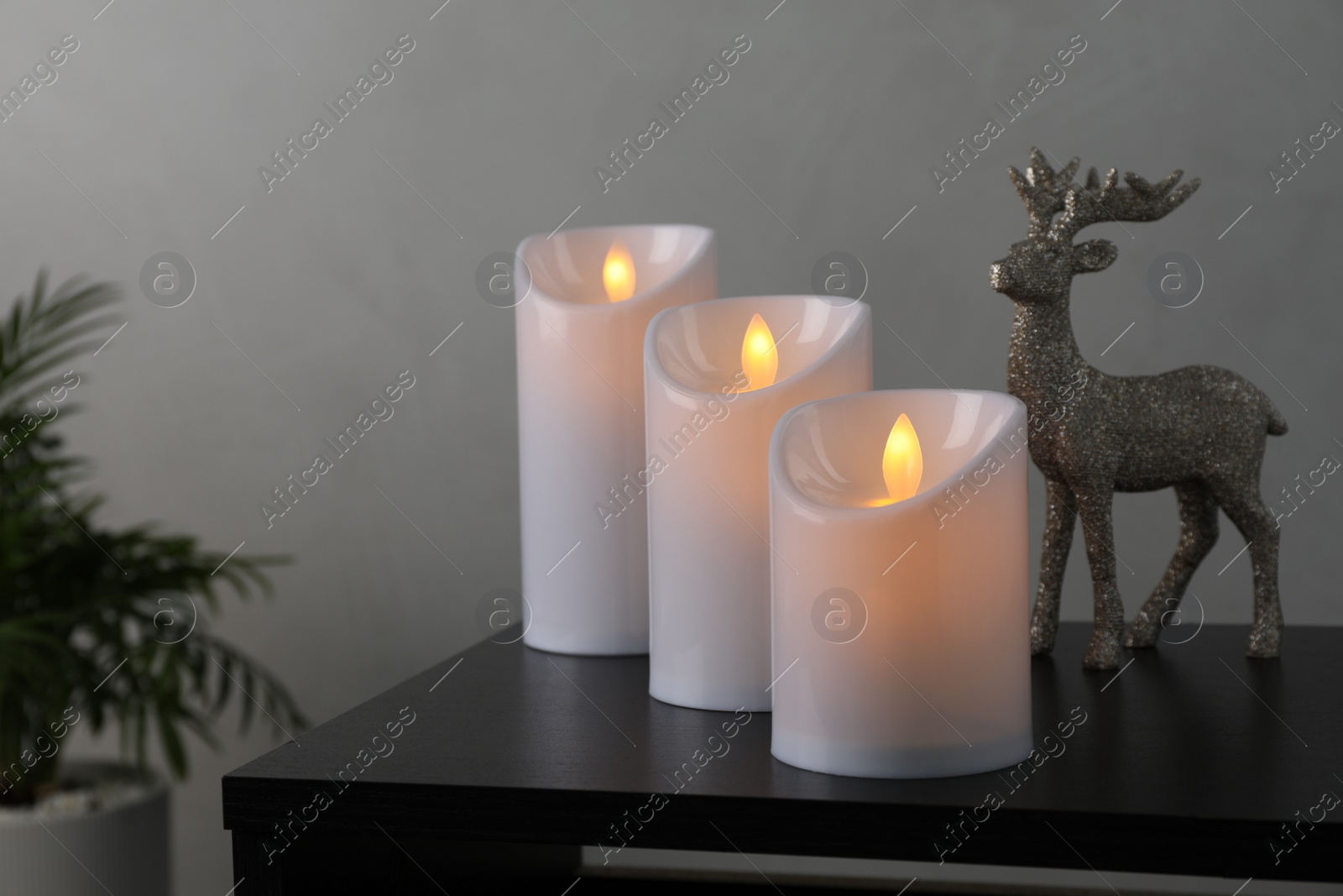 Photo of Glowing decorative LED candles on black table