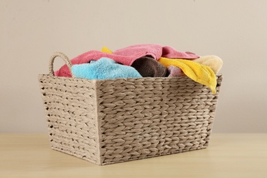 Photo of Wicker laundry basket with towels on wooden table