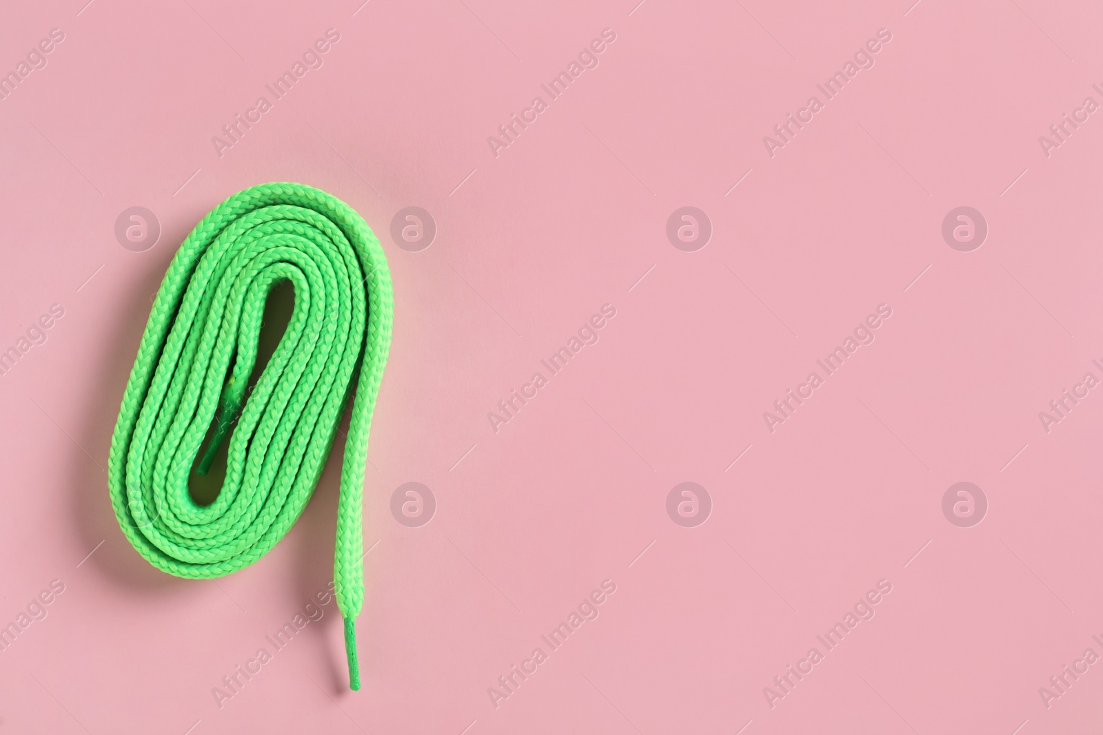 Photo of Green shoelace on pink background, top view. Space for text
